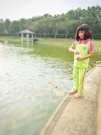 Girl standing by lake against plants