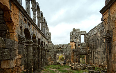 Woman walking at old ruins against sky