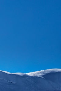 Low angle view of snowcapped mountain against clear blue sky