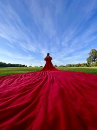 Rear view of woman standing on field against sky