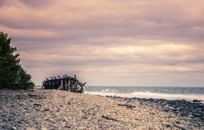 View of calm beach against cloudy sky
