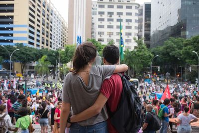 Rear view of friends standing against buildings in city