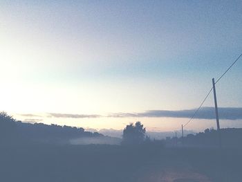 View of calm countryside lake against mountain range in foggy weather