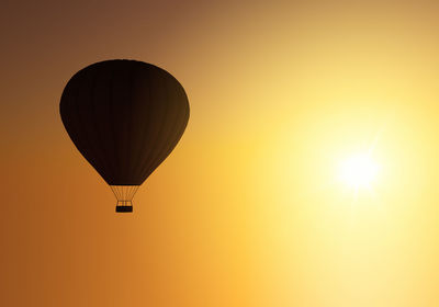 Hot air balloon flying against sky during sunset