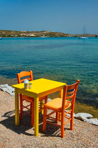 Chairs and tables at beach against blue sky