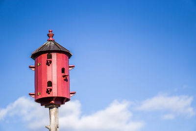 Low angle view of red birdhouse against sky