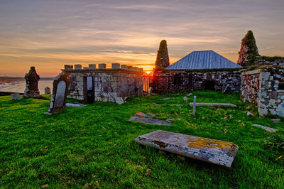 Built structure on field against sky during sunset