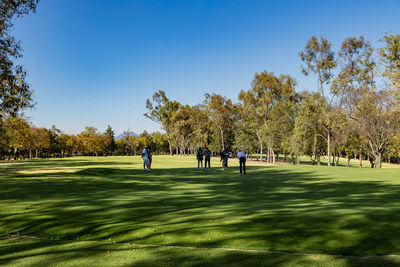 Group of people on golf course against blue sky