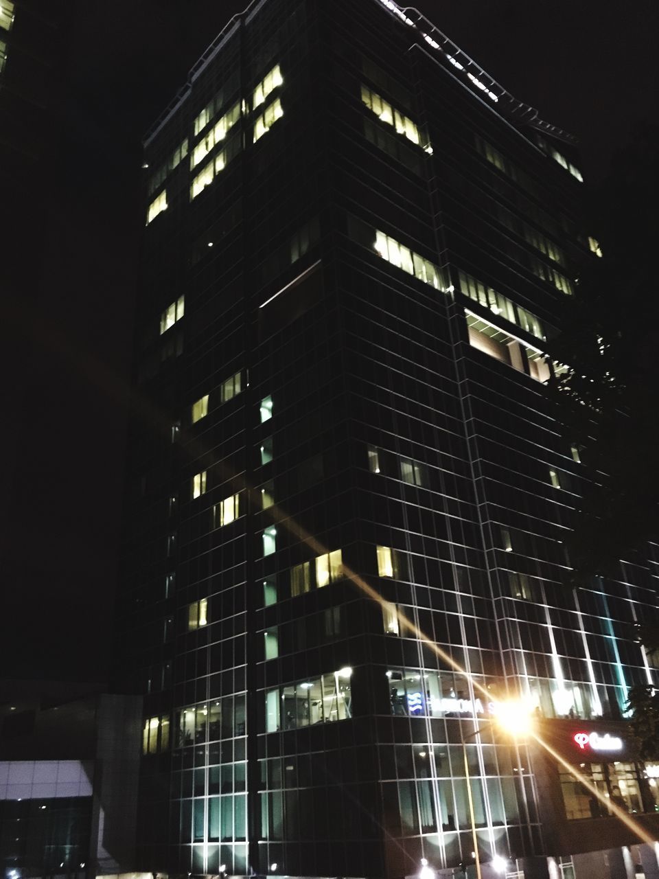 LOW ANGLE VIEW OF ILLUMINATED SKYSCRAPERS AT NIGHT