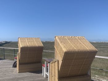 Empty chairs on beach against clear blue sky