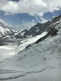 Snow covered mountains against cloudy sky