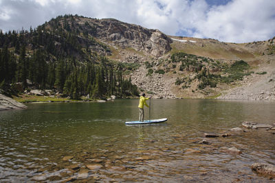 Man paddleboarding in lake during summer