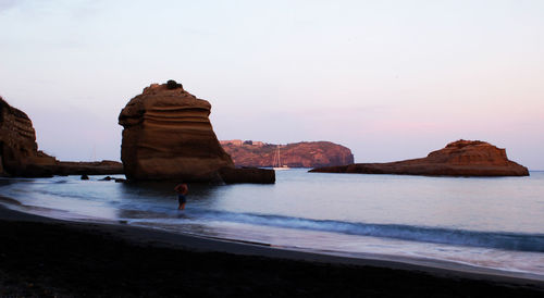 Rock formation on beach against sky