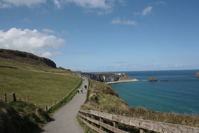 Scenic view of road by sea against sky