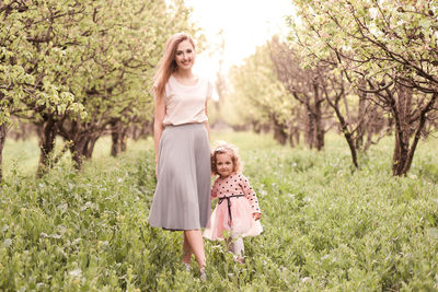 Portrait of mother and daughter standing on grass