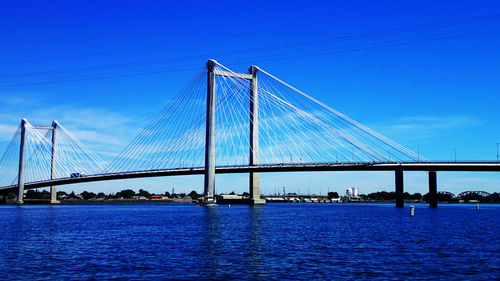 Suspension bridge over river against blue sky