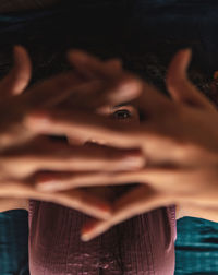 Close-up portrait of with hands clasped in darkroom