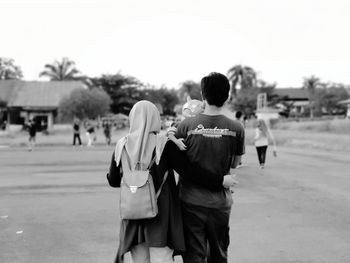 Rear view of couple standing against sky