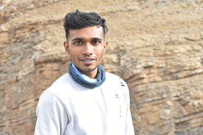 Portrait of young man standing against rock