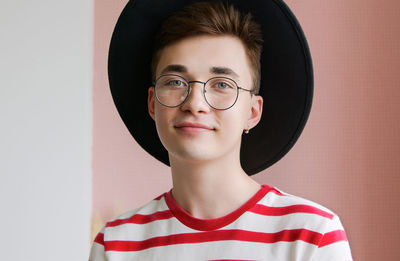 Close-up portrait of young man wearing hat against wall