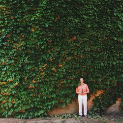 Man standing against ivy covered wall