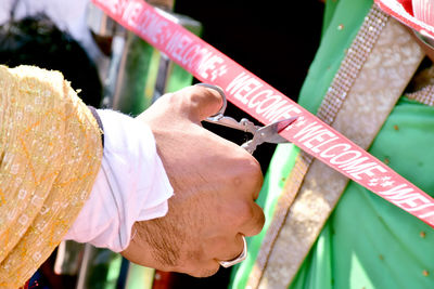 Cropped hand of man cutting ribbon with scissors