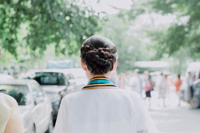 Rear view of woman on road in city against trees