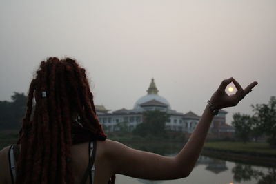 Rear view of woman photographing against clear sky