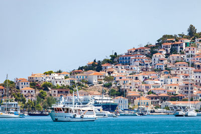 Sailboats moored in harbor by buildings in city against clear sky