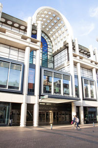 People walking on modern building against sky in city