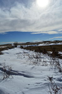 Scenic view of snow covered field against cloudy sky
