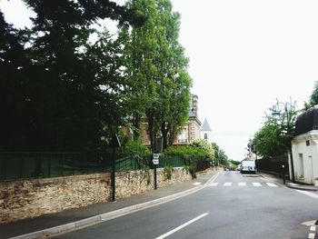 Road amidst trees and buildings against clear sky