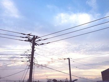 Low angle view of silhouette electricity pylon against sky