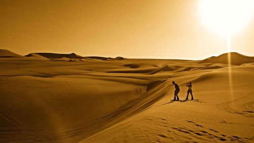 Man and woman standing at desert during sunset