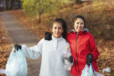 Portrait of female environmentalists holding plastic waste in park