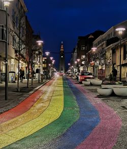 Illuminated street amidst buildings in city at night