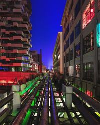 Railroad tracks amidst buildings in city against sky at night