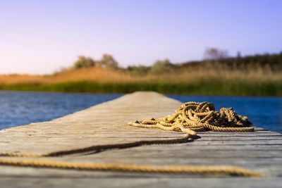 Close-up of rope on wood against lake