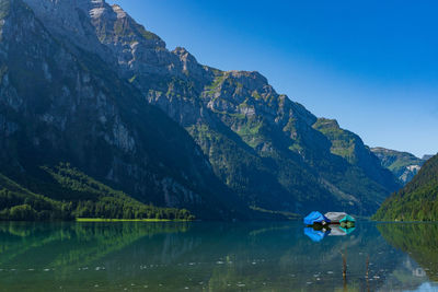 Scenic view of lake and mountains against blue sky