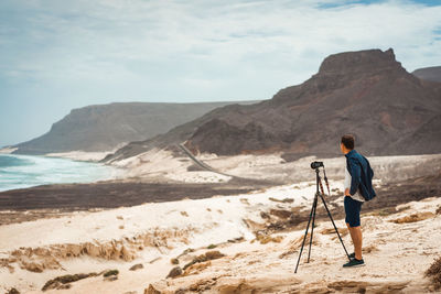 Rear view of man standing on shore against sky