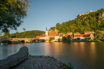 Scenic view of river by buildings against sky