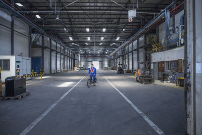 Worker on bicycle in warehouse