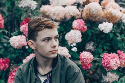 Portrait of young man against white flowering plants