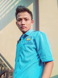 Portrait of young man standing against blue wall