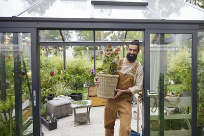 Smiling man holding potted flowers