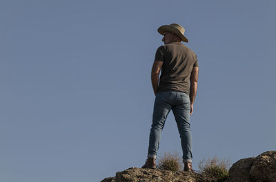 Adult man in cowboy hat standing on top of cliff in tabernas desert, almeria, spain