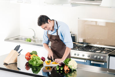 Young man preparing food in kitchen at home