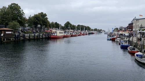 Boats moored in river against sky in city