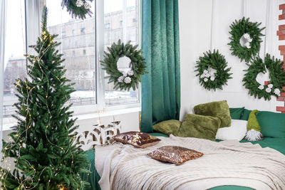 The bedroom decorated by christmas. cozy light interior plaid, wooden bed and christmas fir-tree .