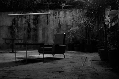 Empty armchair by table in backyard at night